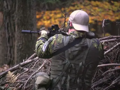 Airsoftový hráč při krytí za větvemi v podzimním lese